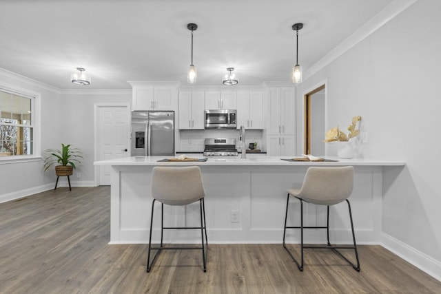 kitchen featuring appliances with stainless steel finishes, tasteful backsplash, white cabinets, a kitchen bar, and dark wood-type flooring