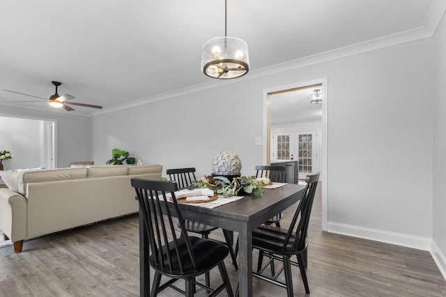 dining area with ceiling fan with notable chandelier, wood-type flooring, and ornamental molding