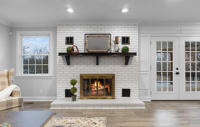 unfurnished living room featuring crown molding, hardwood / wood-style floors, a brick fireplace, and french doors