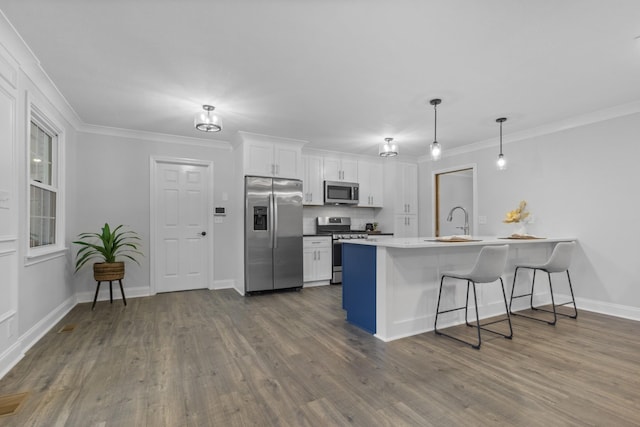 kitchen with dark wood-type flooring, a kitchen bar, white cabinetry, decorative light fixtures, and stainless steel appliances