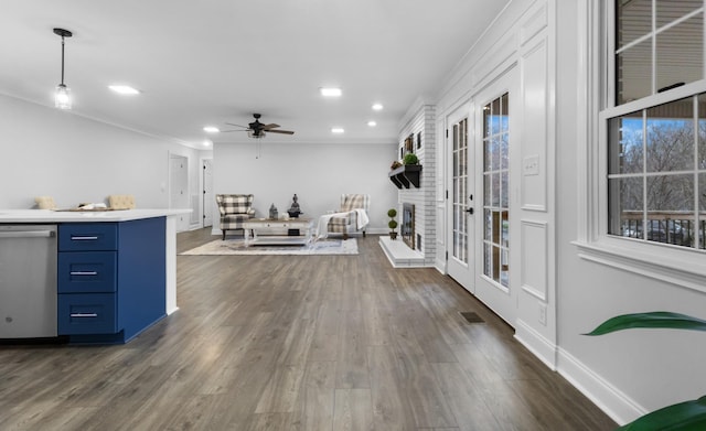 living room with a healthy amount of sunlight, a brick fireplace, dark wood-type flooring, and ceiling fan