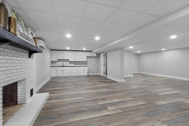 interior space with sink, light wood-type flooring, a brick fireplace, and an AC wall unit