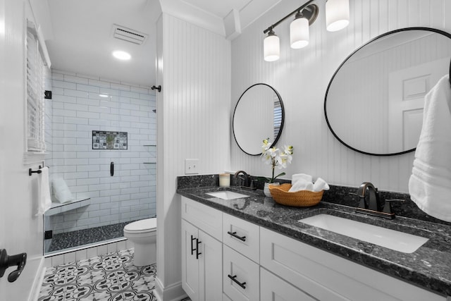 bathroom featuring tile patterned flooring, vanity, a shower with shower door, and toilet