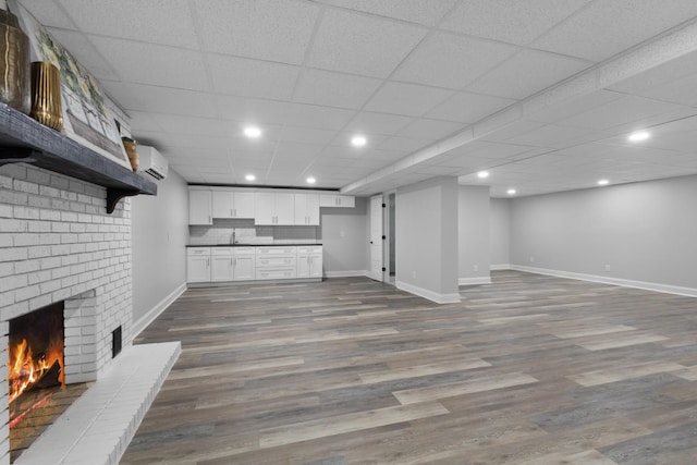 interior space with a wall mounted air conditioner, sink, hardwood / wood-style floors, and a brick fireplace