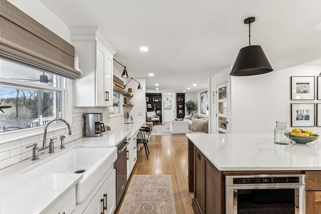 kitchen featuring white cabinetry, sink, and light stone counters