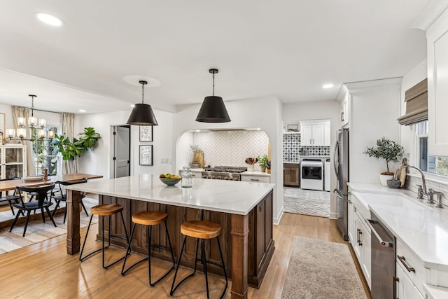 kitchen featuring white cabinetry, stainless steel appliances, decorative light fixtures, and a center island