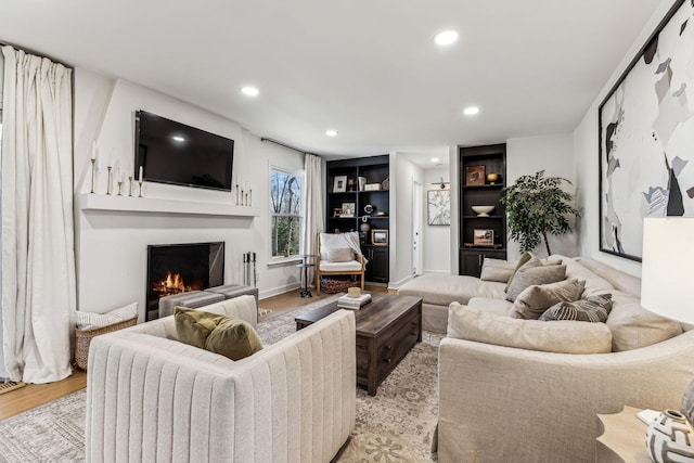 living room with built in features and light hardwood / wood-style flooring