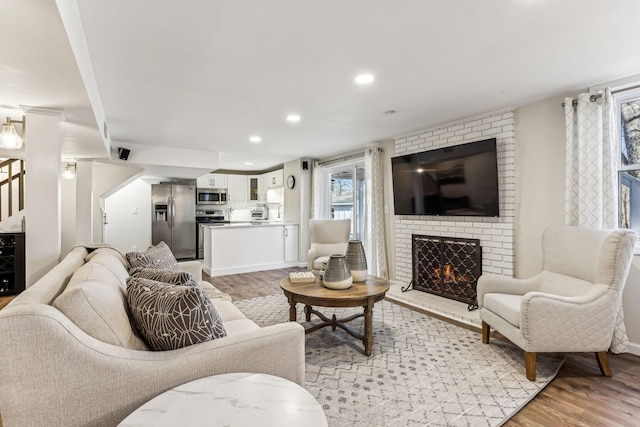 living room with a brick fireplace and light hardwood / wood-style floors