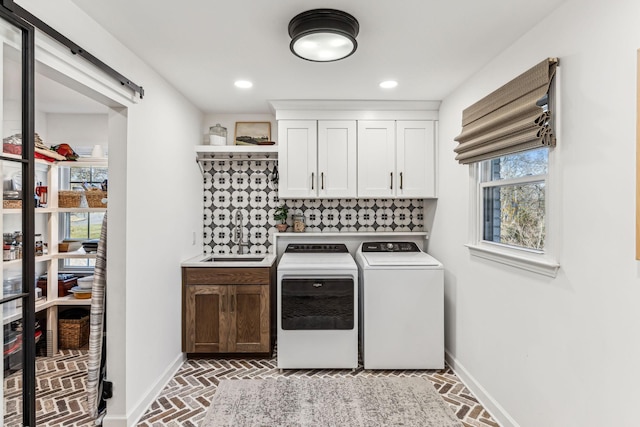 washroom featuring cabinets, washing machine and clothes dryer, a barn door, and sink