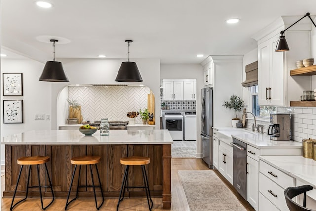 kitchen featuring white cabinetry, sink, washer and dryer, and stainless steel refrigerator