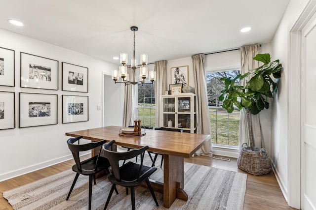 dining space with hardwood / wood-style flooring, a healthy amount of sunlight, and a notable chandelier