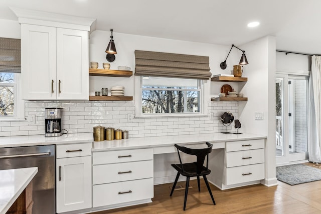 kitchen featuring white cabinetry, dishwasher, built in desk, and light wood-type flooring