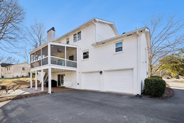 rear view of property featuring ceiling fan, a garage, and a sunroom