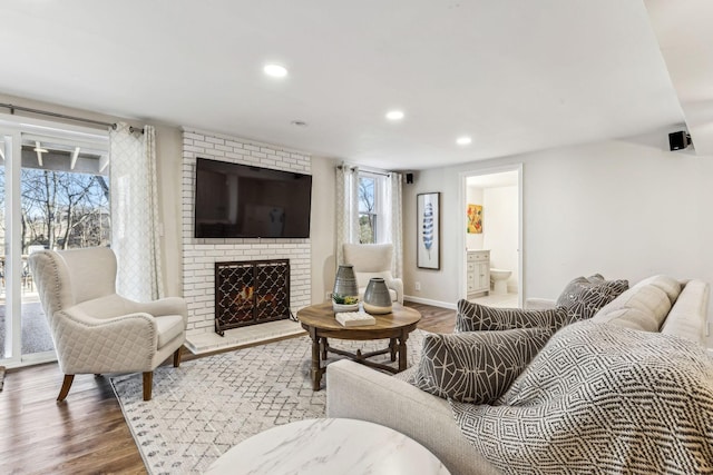 living room with wood-type flooring and a brick fireplace