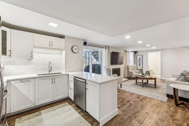 kitchen featuring sink, white cabinetry, stainless steel dishwasher, dark hardwood / wood-style flooring, and kitchen peninsula