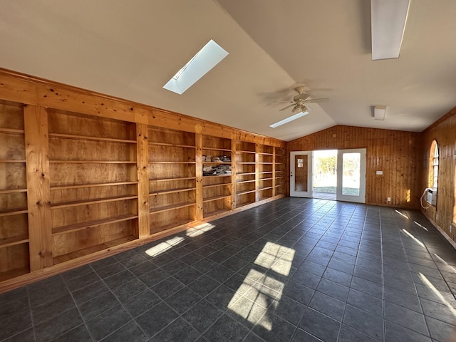 spare room featuring wooden walls, dark tile patterned flooring, built in features, cooling unit, and vaulted ceiling with skylight