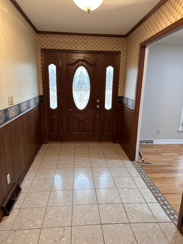 foyer entrance with ornamental molding and light tile patterned flooring