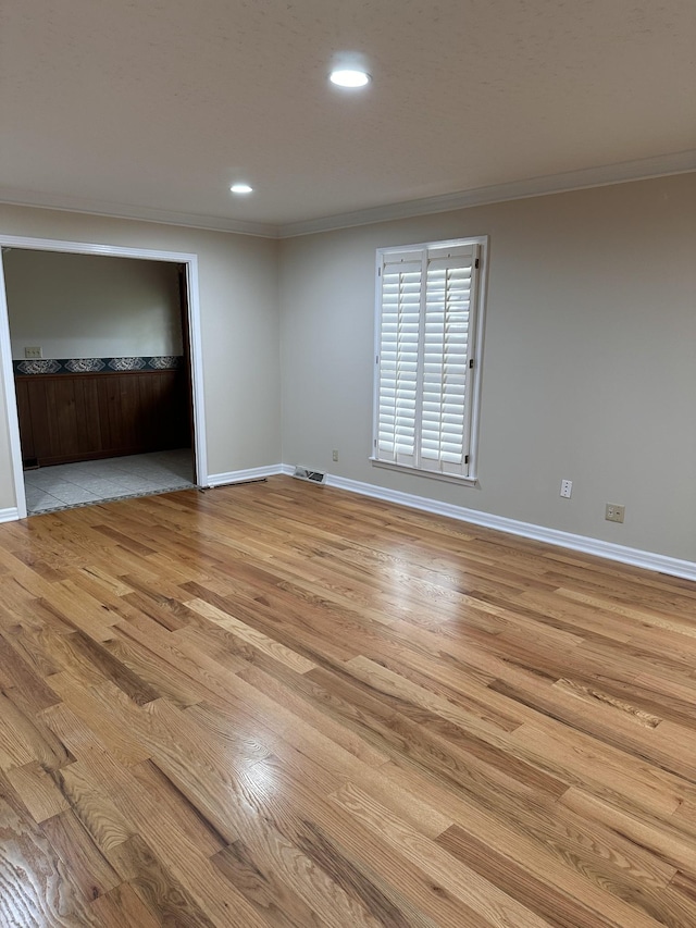 empty room featuring crown molding and light hardwood / wood-style floors