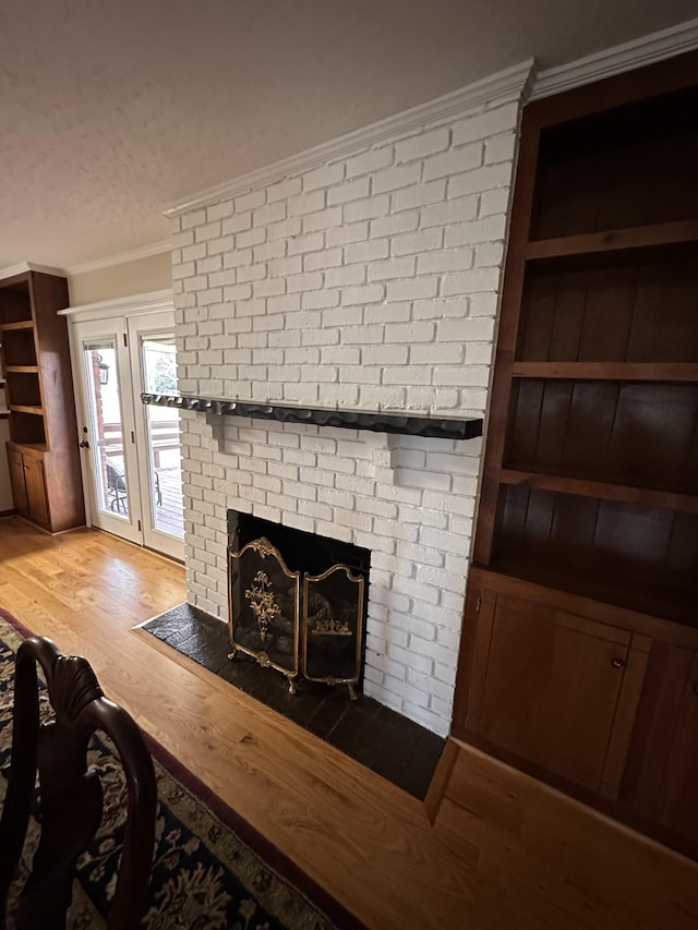 interior details with a brick fireplace, crown molding, wood-type flooring, and a textured ceiling