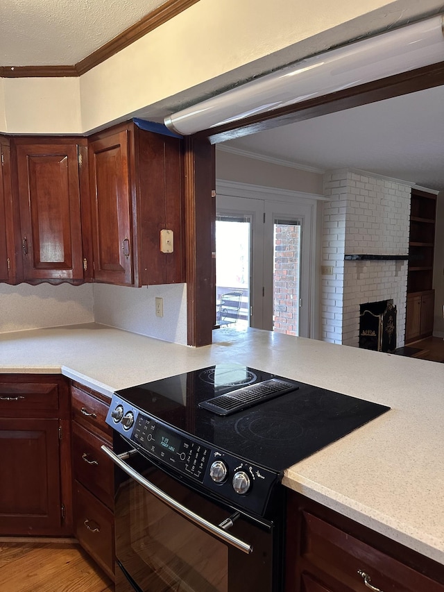 kitchen with ornamental molding, a brick fireplace, light hardwood / wood-style flooring, and black range with electric cooktop