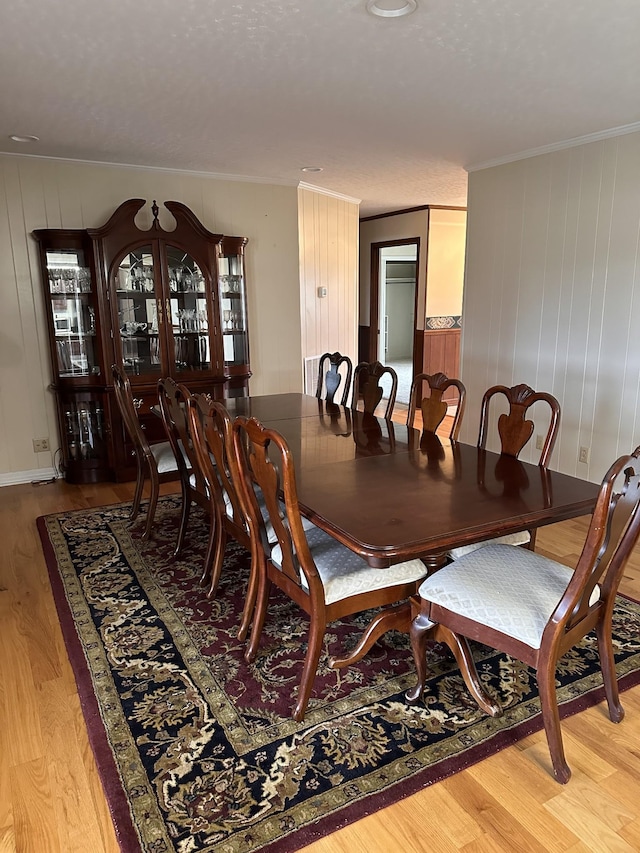 dining space featuring ornamental molding and light hardwood / wood-style flooring