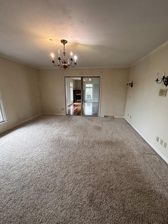 unfurnished room featuring an inviting chandelier, crown molding, a textured ceiling, and carpet flooring