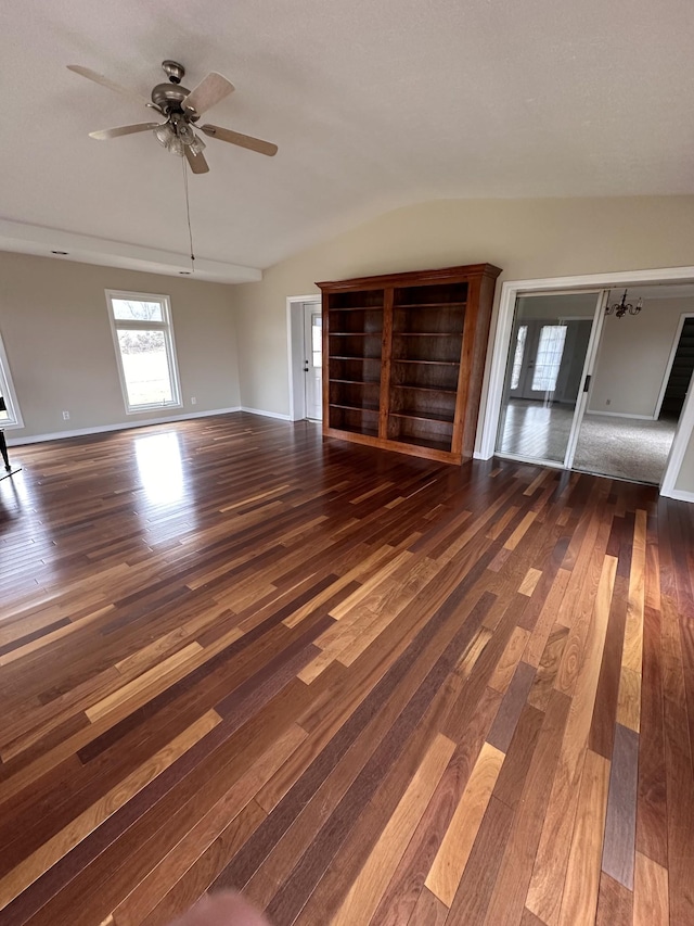 unfurnished living room featuring dark wood-type flooring and ceiling fan