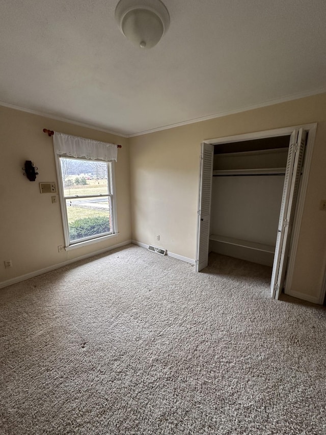 unfurnished bedroom with crown molding, carpet floors, and a closet