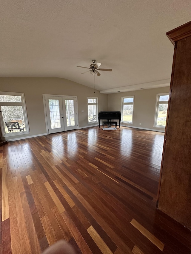 unfurnished living room featuring dark wood-type flooring, french doors, vaulted ceiling, a textured ceiling, and ceiling fan