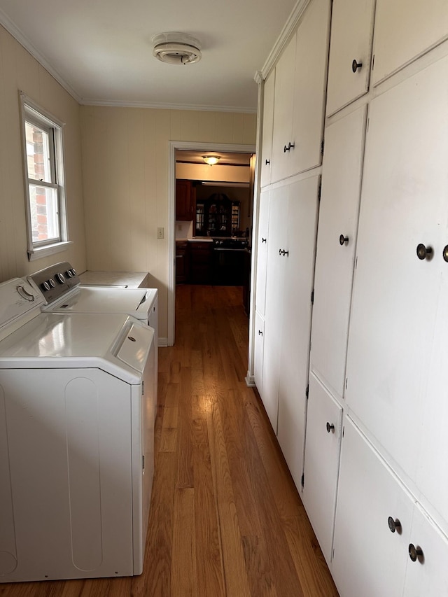 laundry area featuring independent washer and dryer, cabinets, crown molding, and light hardwood / wood-style flooring