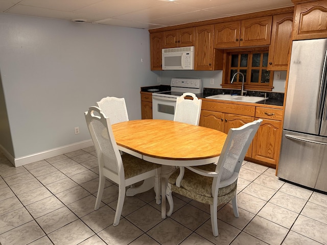 kitchen with white appliances, a paneled ceiling, sink, and light tile patterned floors