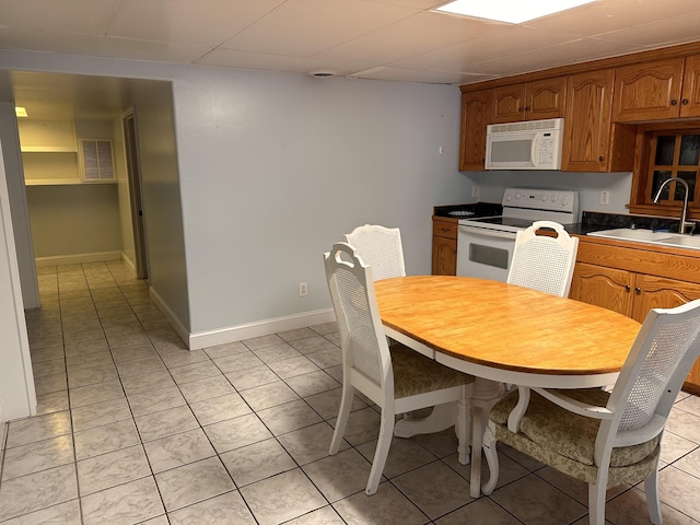 kitchen featuring sink, white appliances, a paneled ceiling, and light tile patterned flooring