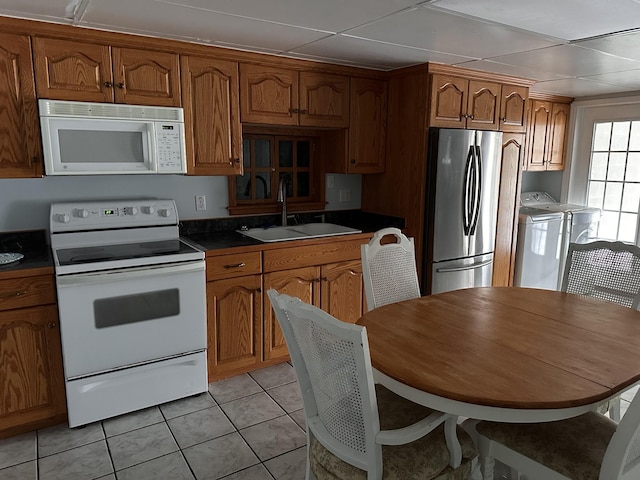 kitchen with separate washer and dryer, sink, white appliances, and light tile patterned flooring