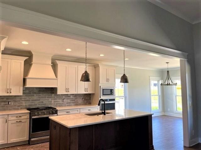 kitchen with appliances with stainless steel finishes, decorative light fixtures, white cabinetry, sink, and custom range hood