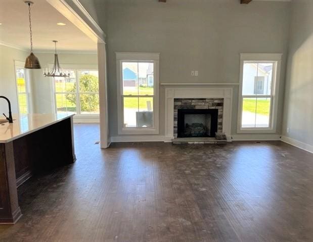 unfurnished living room featuring plenty of natural light, dark hardwood / wood-style floors, and a stone fireplace