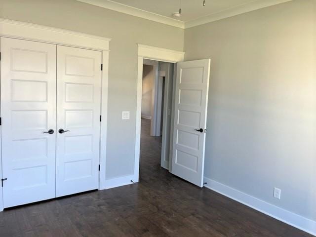 unfurnished bedroom with crown molding, dark wood-type flooring, and a closet