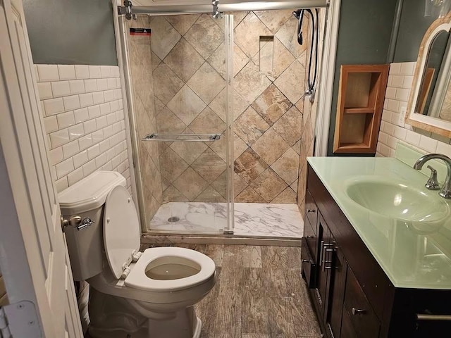 bathroom featuring vanity, a shower with shower door, toilet, and tile walls