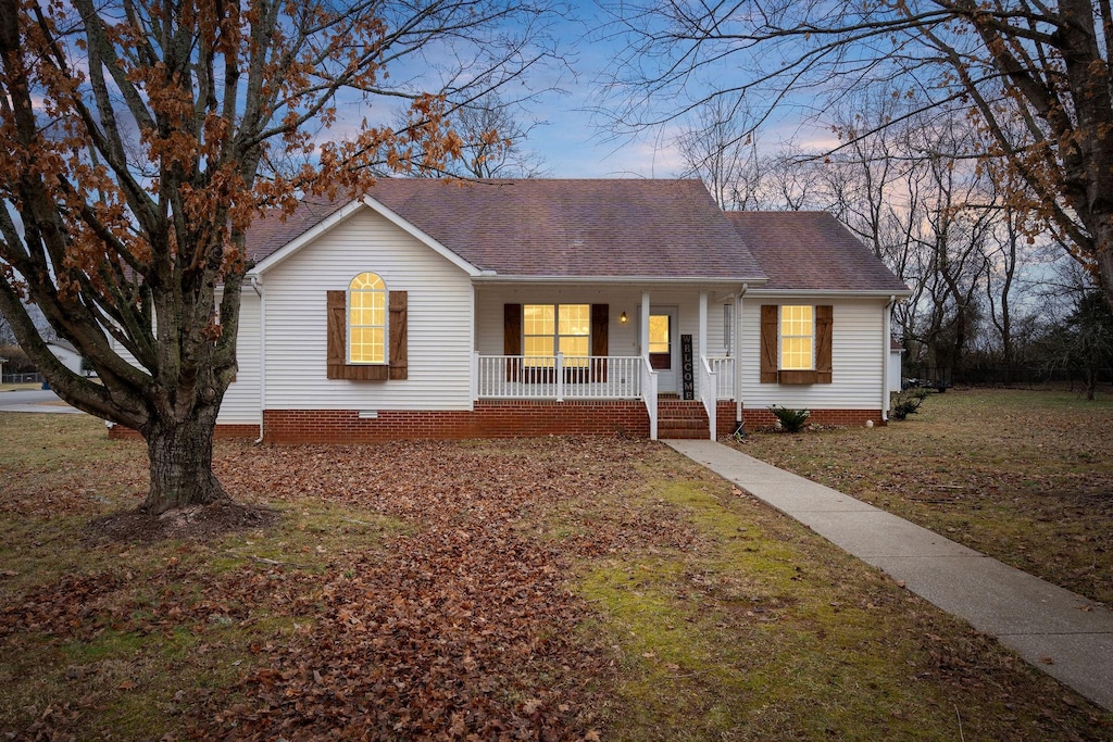 ranch-style house featuring covered porch and a lawn