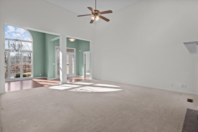 spare room featuring a towering ceiling, ceiling fan, and carpet flooring