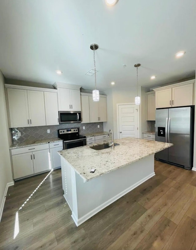 kitchen featuring appliances with stainless steel finishes, sink, pendant lighting, and a kitchen island with sink