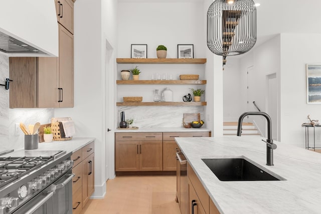 kitchen featuring premium range hood, sink, light stone counters, pendant lighting, and range with two ovens