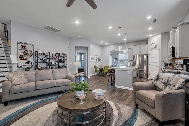 living room featuring dark wood-type flooring and ceiling fan