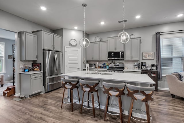 kitchen with stainless steel appliances, gray cabinets, sink, and decorative light fixtures