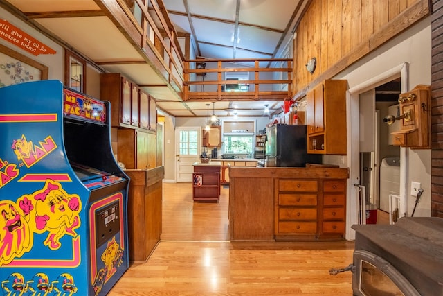 kitchen featuring black fridge, kitchen peninsula, light hardwood / wood-style flooring, and pendant lighting