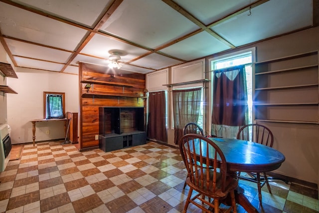 dining space with coffered ceiling, wooden walls, and ceiling fan