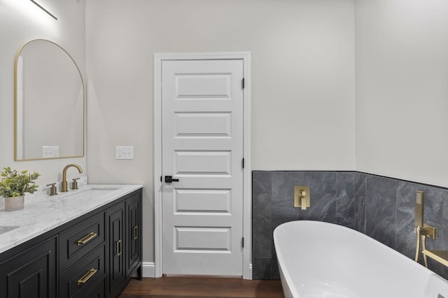 bathroom with hardwood / wood-style flooring, vanity, a bath, and tile walls