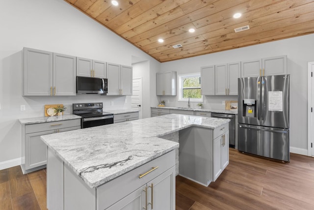 kitchen with vaulted ceiling, stainless steel appliances, a center island, and sink