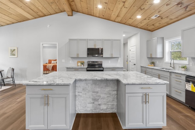 kitchen featuring electric range oven, light stone countertops, sink, and a kitchen island