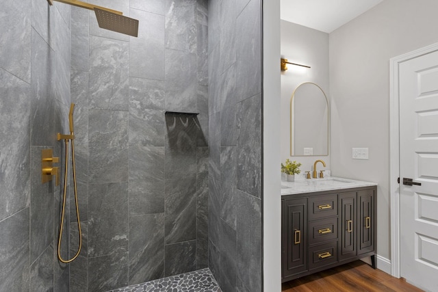 bathroom featuring tiled shower, wood-type flooring, and vanity