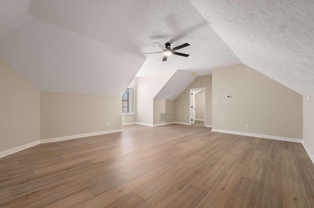 additional living space with vaulted ceiling, ceiling fan, light hardwood / wood-style floors, and a textured ceiling